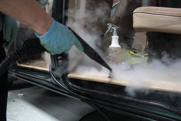 A Detailer Steam Cleaning the interior of a car